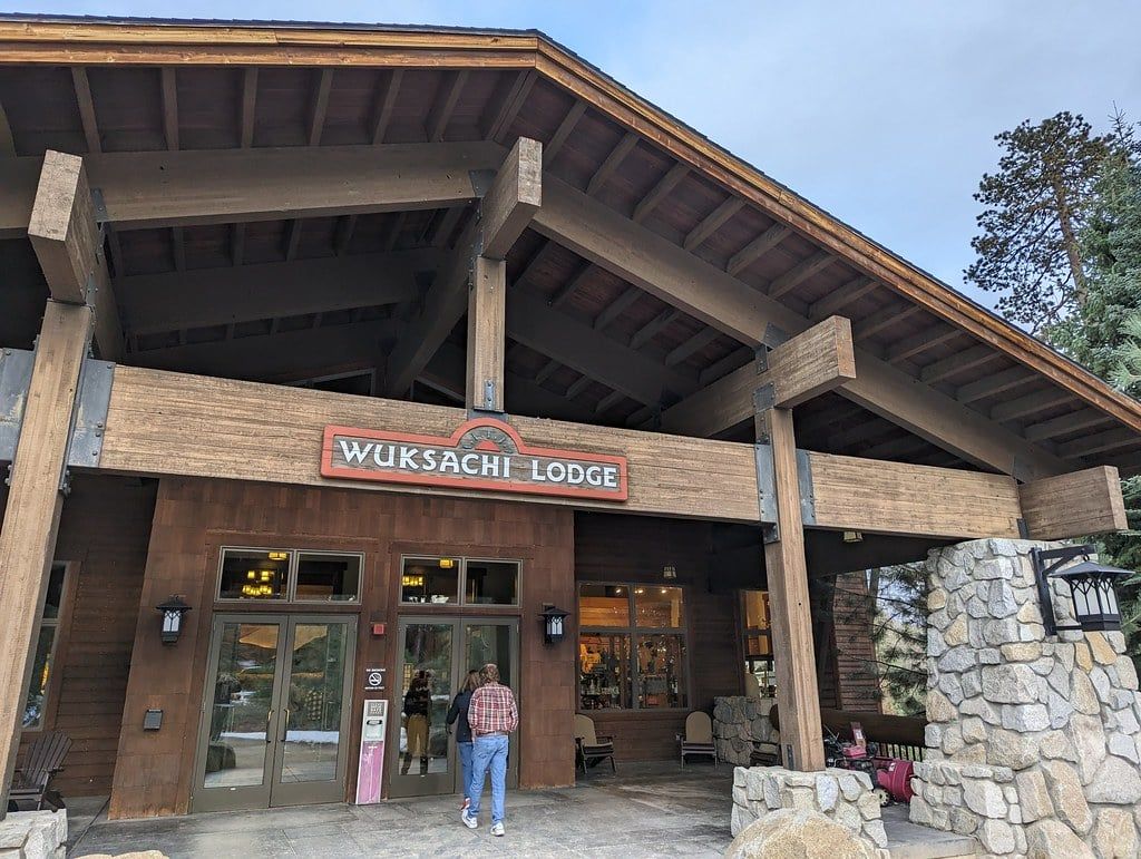 Visitantes caminan hacia la entrada principal de Wuksachi Lodge bajo un techo de vigas de madera maciza en el Parque Nacional Sequoia.